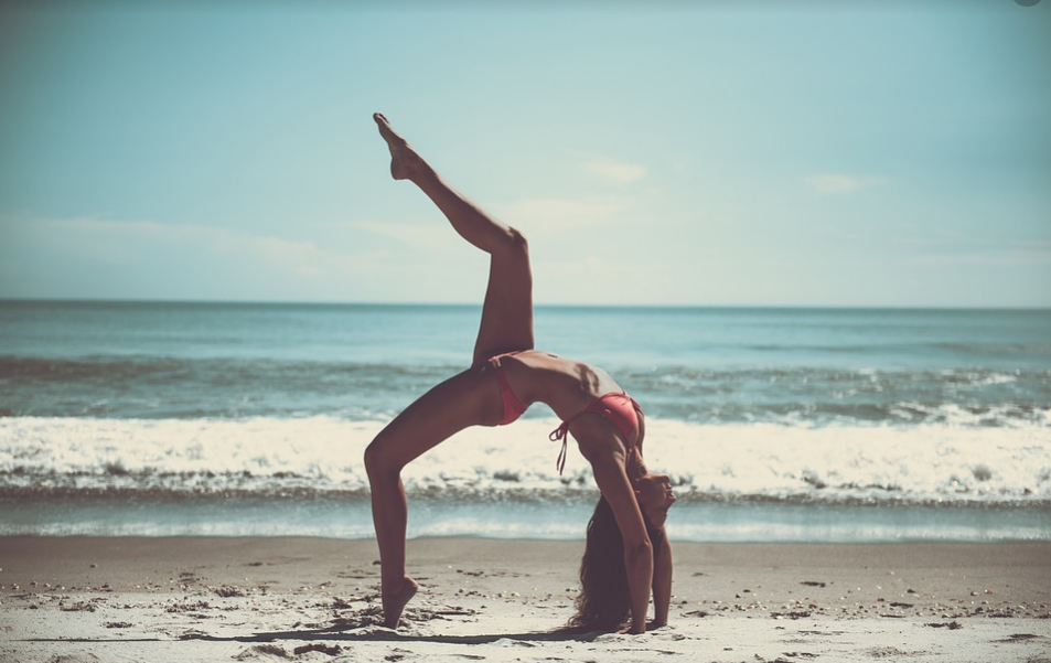 girl doing a yoga pose on a beach